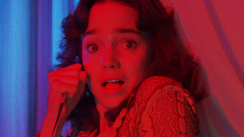 Suzy scared, bathed in red/blue light