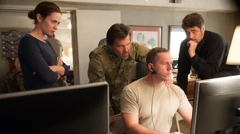 Kate, Matt, and Alejandro surround a computer screen in "Sicario" (2015)