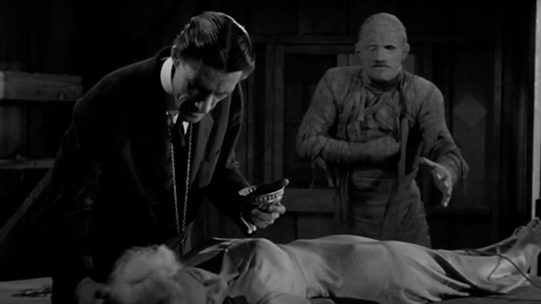 Yousef Bay giving a drink to Amina Mansouri while Kharis lumbers toward them in "The Mummy's Ghost"