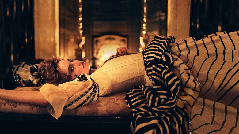 Emma Stone as Abigail dressed for a gala reclining on a couch by a fire in The Favourite (2018)