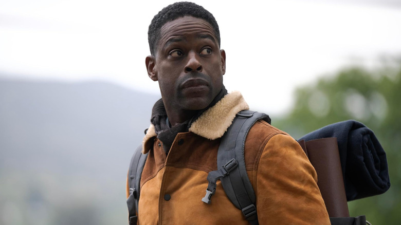 Xavier standing outside with camping gear on his back in Paradise (2025)