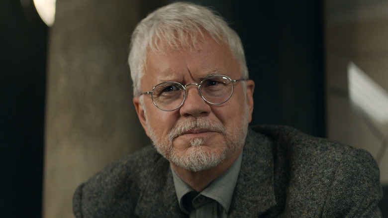 Bernard looking stern in a suit and glasses in Silo (2023)