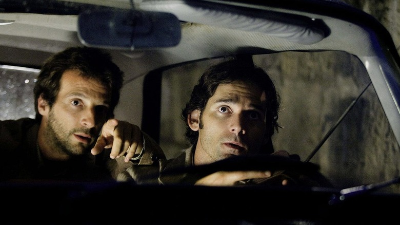 Robert and Avner in a car pointing at something in the film Munich