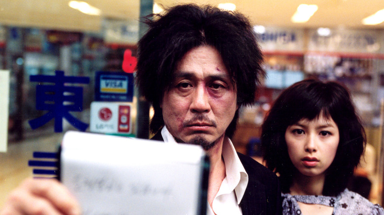 Oh Dae-su holding a piece of paper up next to Mi-do in the movie Oldboy