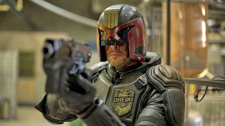 Judge Dredd points a gun with his black and red helmet and body armor in "Dredd" (2012)