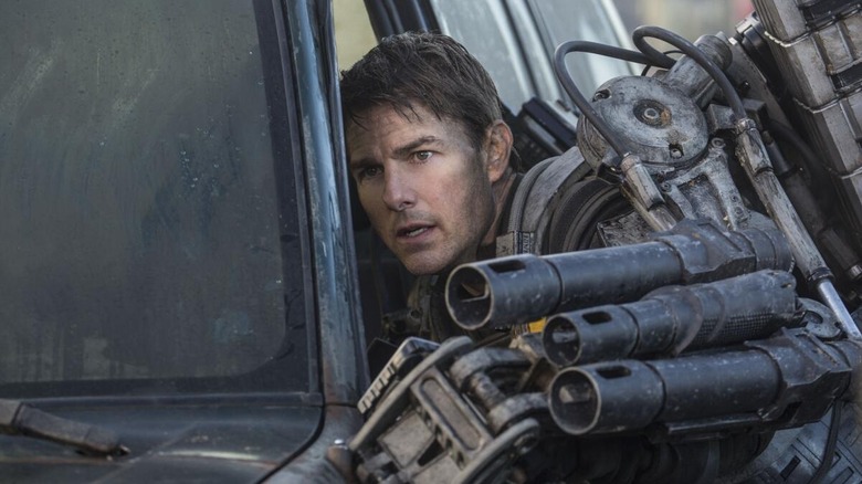 Major William Cage hides behind a car in 'Edge of Tomorrow' (2014)