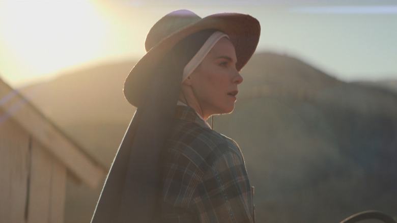 A shot of Simone, wearing her habit underneath her horseback riding garb, mounted with her profile lit by the sunset