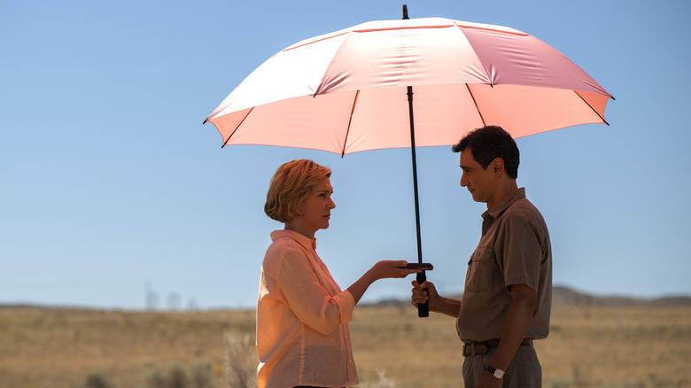 Carol and Manousas chatting under an umbrella against the backdrop of a sunny, arid New Mexico landscape