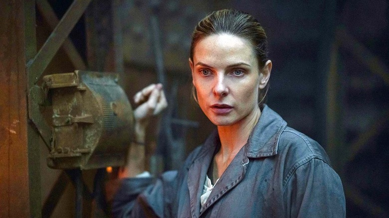 Juliette stands next to machinery on "Silo" (2023-present)