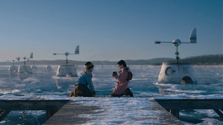 Two children paying on an icy dock with strange tech devices in the background in Tales from the Loop (2020)