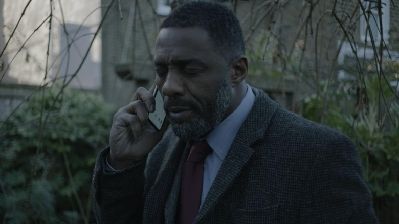 Luther holding a phone with his eyes closed in "Luther"