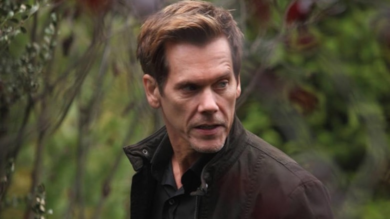 Hardy standing outside, looking to his left, in "The Following"