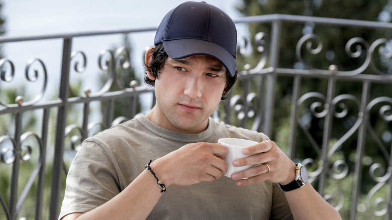 Ethan holding his coffee mug and looking suspicious on 