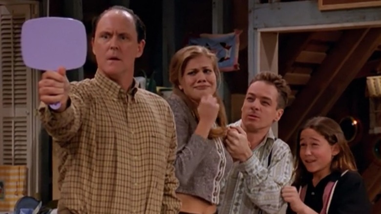 Dick, Sally, Harry, and Tommy Solomon standing together while Dick looks in a mirror in "3rd Rock from the Sun"