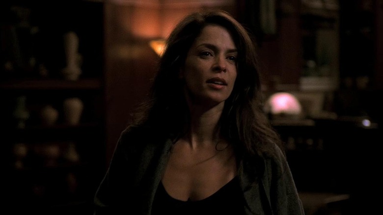 Gloria stands in dark bar