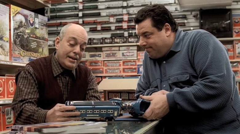 Bobby and shopowner stand by model train counter