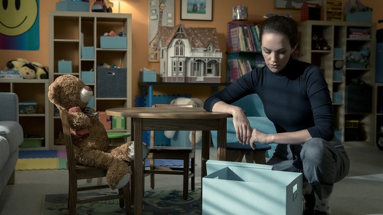 Theo Crain looking into a box while standing next to a teddy bear at a table in "The Haunting of Hill House"