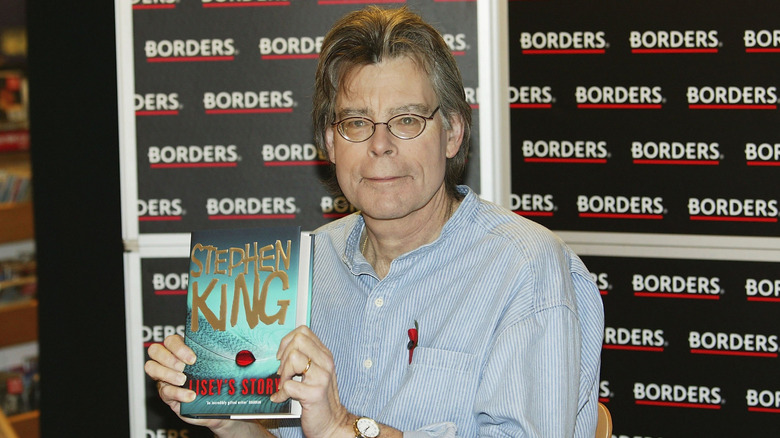 Stephen King posing with his novel 