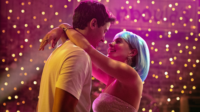 Alex and a blue-wigged Poppy dance in front of colored lights in "People We Meet on Vacation" (2026)