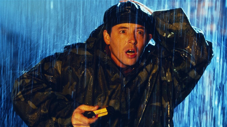 Dr. Niko Tatopoulos looking scared holding camera in the rain in 