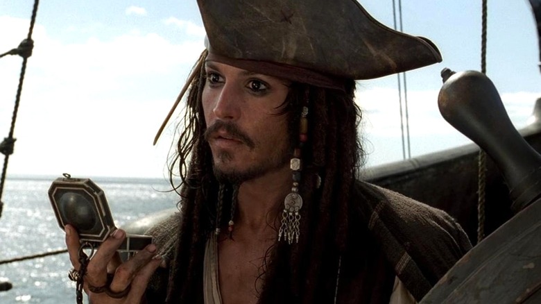 Captain Jack Sparrow holding a compass in "Pirates of the Caribbean: The Curse of the Black Pearl."