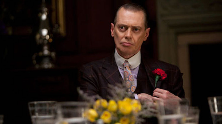 Nucky sits at dinner and affixes a rose to his lapel