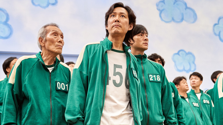 Player 456, Player 218, Player 199, and Player 001 standing with other contestants before the first game (2021)