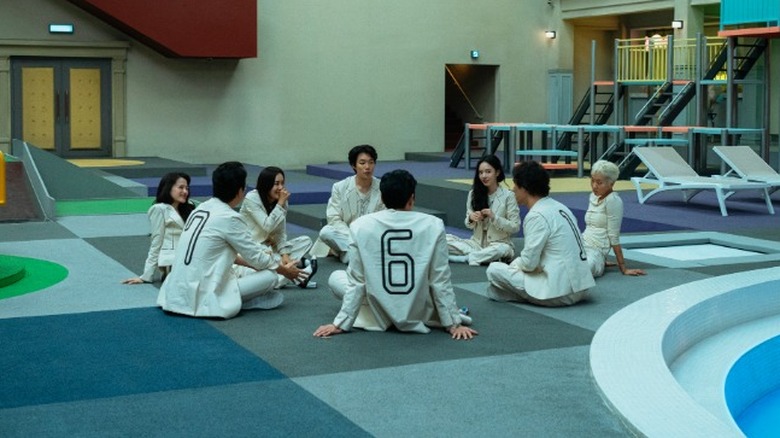 The eight participants sitting in a circle on "The 8 Show" (2024)