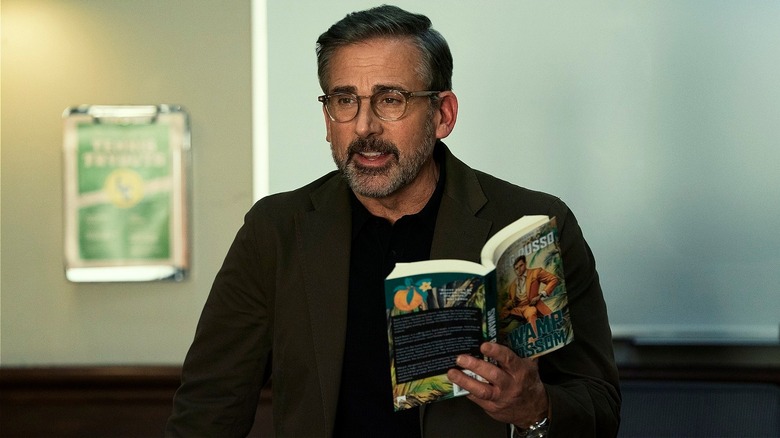 Greg holding a book giving a lecture in Rooster