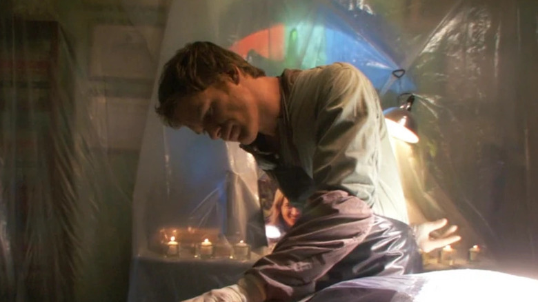 Dexter Morgan grabbing the face of one of his murderous serial killing victims in a room draped in plastic in the series "Dexter"