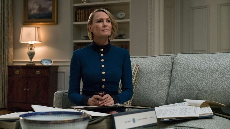 Claire sits on a couch looking over a binder.