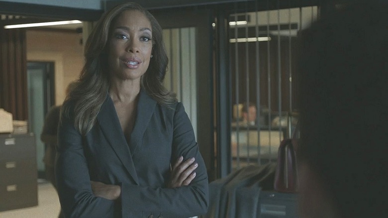 Jessica stands in an office with her arms folded.