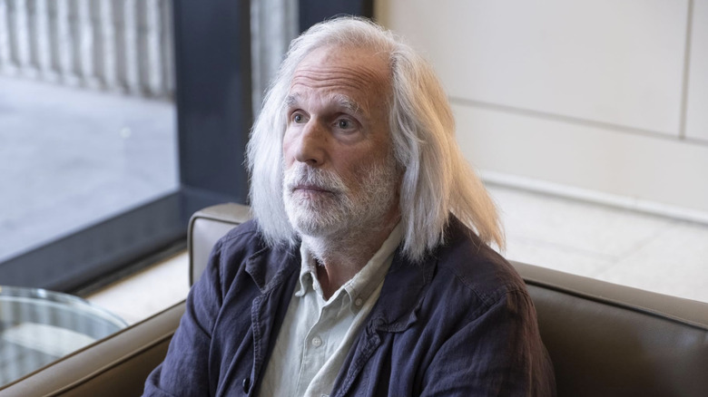 Gene Cousineau sitting in brown leather chair with long white hair and beard