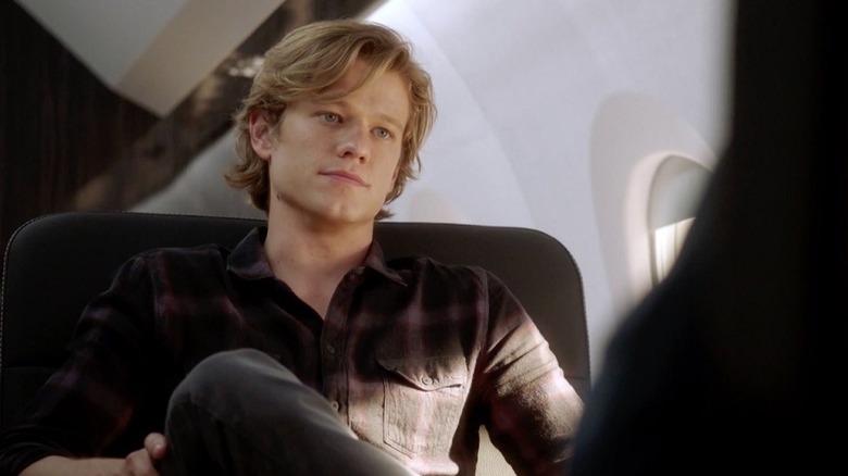 Mac leans back in his seat on an airplane in MacGyver