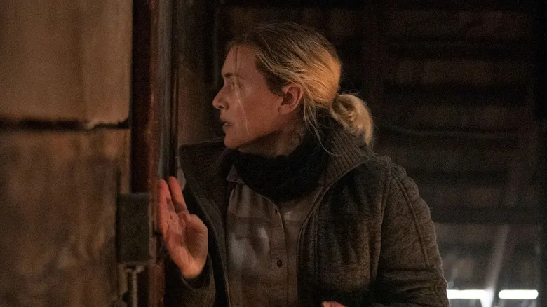 Mare peers through a window in "Mare of Easttown" (2021)