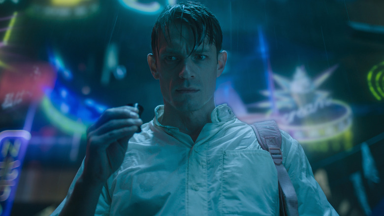 Kovacs holding a small item in the rain in Altered Carbon