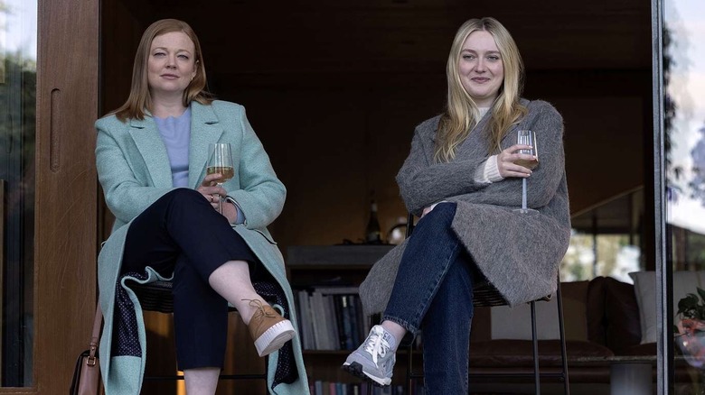 Marissa and Jenny sitting in a patio doorway drinking wine in "All Her Fault"