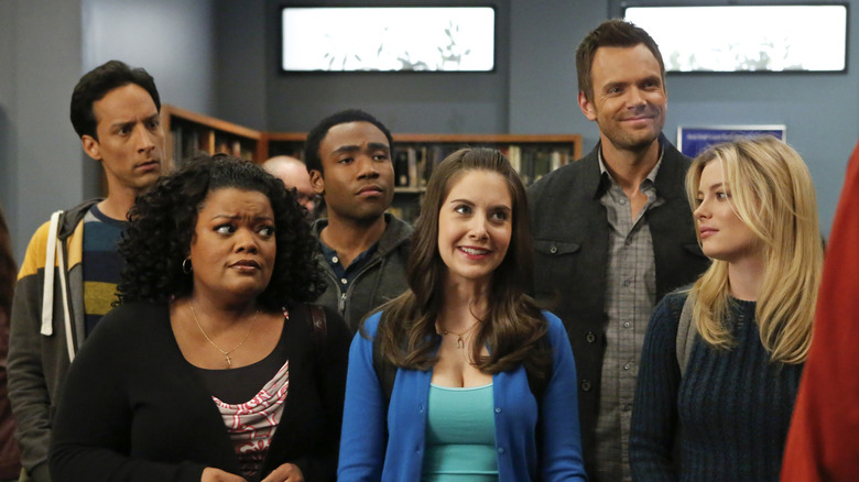 Abed, Shirley, Troy, Annie, Jeff, and Britta standing together in the library
