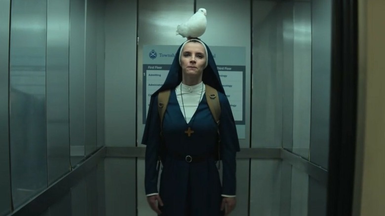 Sister Simone (in her habit) standing in an elevator with a white dove perched on her head