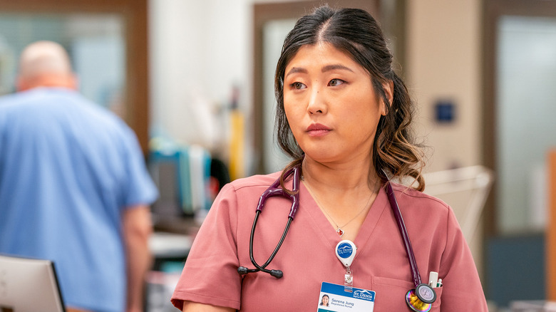 ER nurse Serena looking to the side while wearing pink scrubs