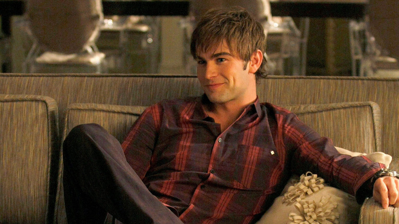 Nate, in a flannel shirt, smirking on couch on Gossip Girl