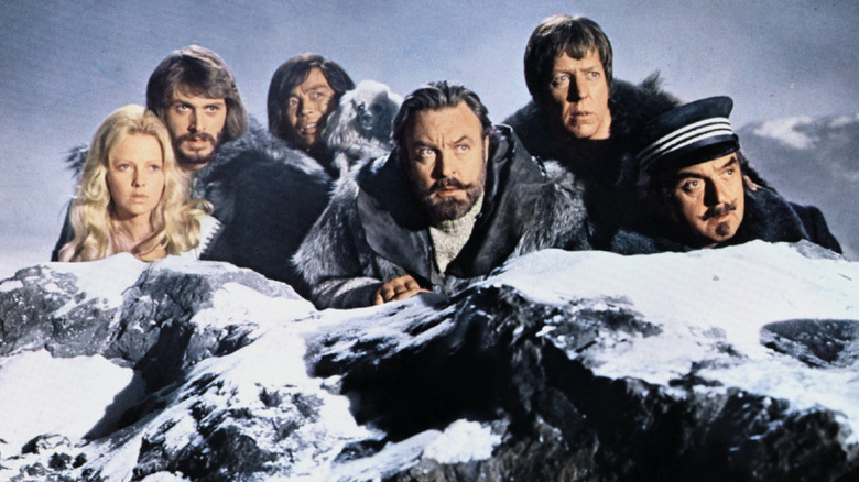 Sir Anthony and his crew peer out over a rocky crag in The Island at the Top of the World (1974)