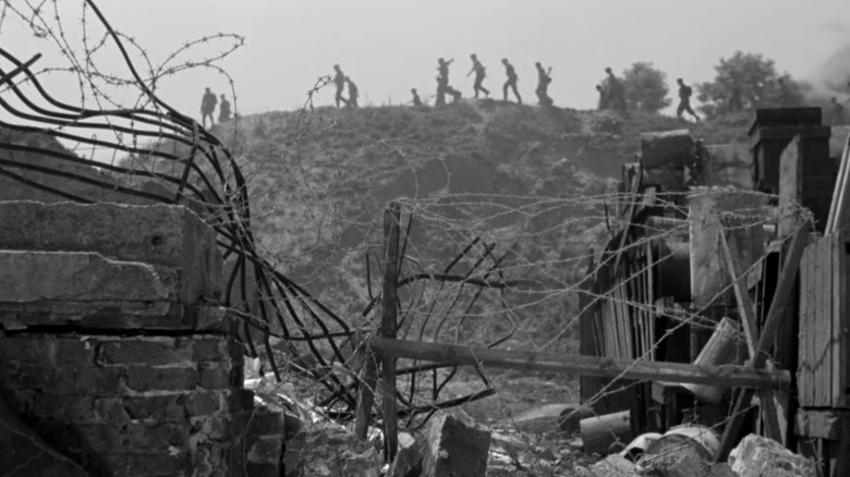 Soldiers marching on hill behind barbed wire in "Kanał"