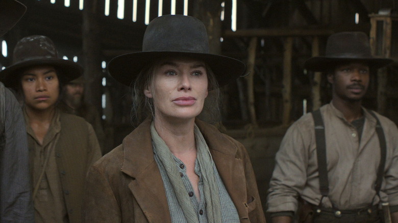 Fiona standing with people in a barn in "The Abandons" (2025)
