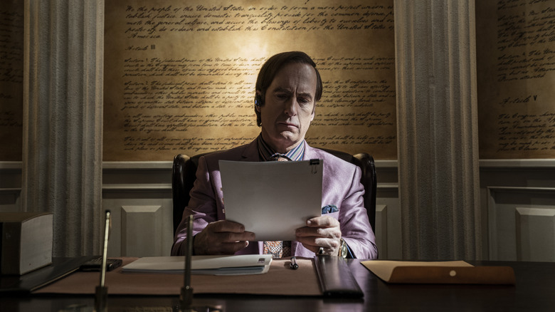 Saul glowering at a packet of papers