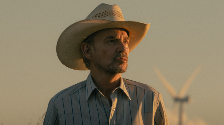 Tommy looking in the distance in front of windmills in 