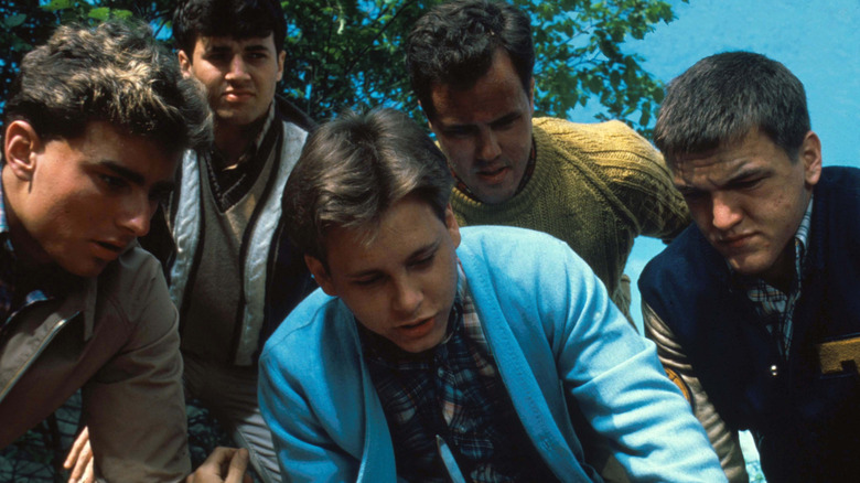 A group of teenagers hovering over someone in 'The Outsiders' (1990)