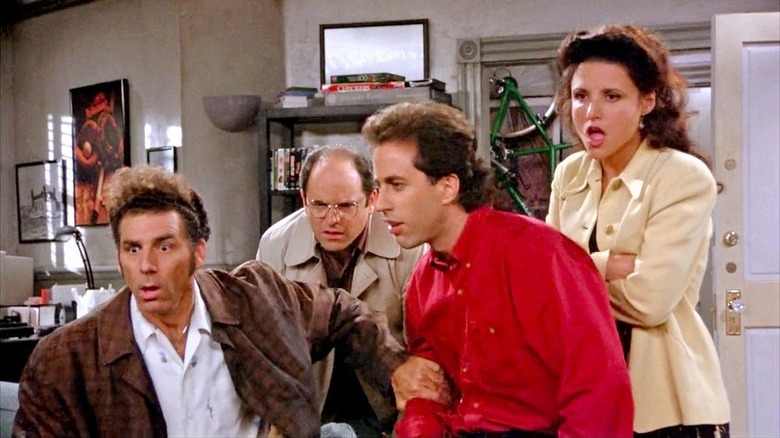 Jerry, George, Elaine, and Kramer watch the TV in shock in "Seinfeld"