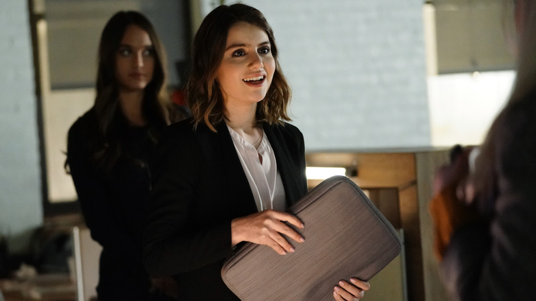 Nicky Reagan smiles and holds a carrying case in "Blue Bloods"