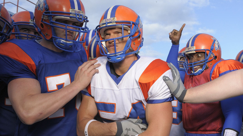 Thad scowling in football gear with teammates patting his shoulders
